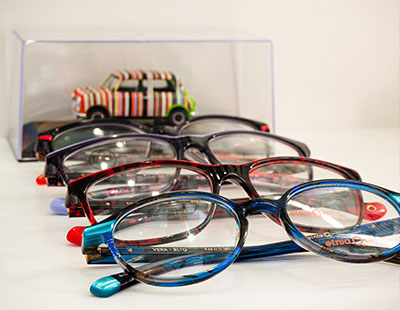The image displays a collection of eyeglasses with various frame colors and designs on display.